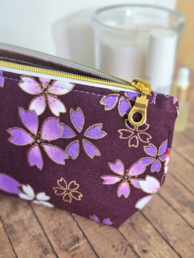 Close up of gold foiled purple fabric toiletries bag with gold zip.