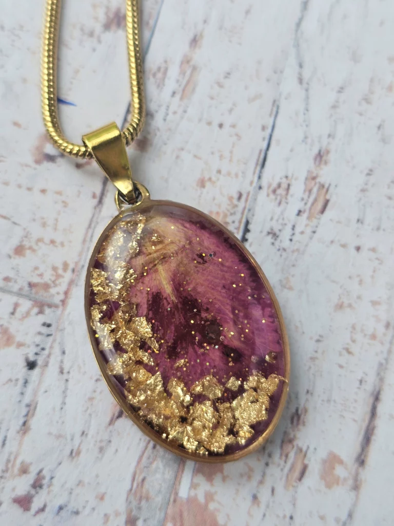 Close up of handmade rose petal bezel necklace pendant. The characteristics of a rose petal is complimented by soft gold flakes in a soft wave on one side of the bezel.